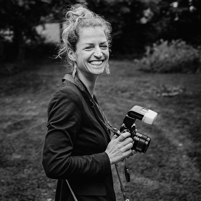 Selbstportrait der lachenden und strahlenden Seelenfotografin Lissy Routil mit ihrer Kamera in der Hand.