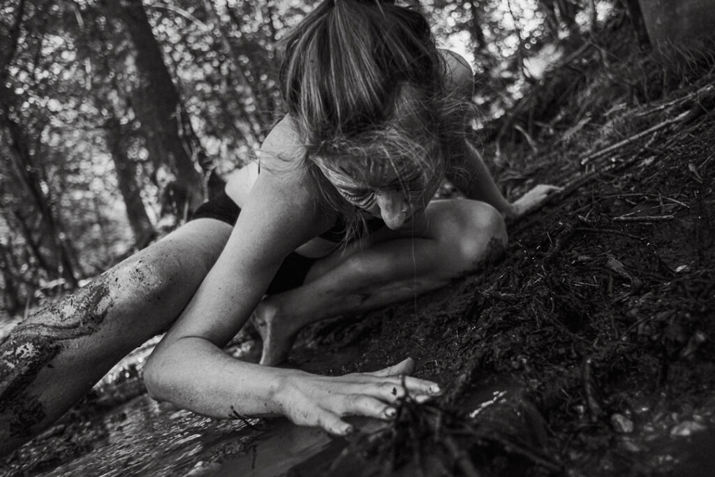 Soul Photo einer leicht bekleideten Frau auf dem Waldboden während eines intensiven Shootings mit Seelenfotografin.